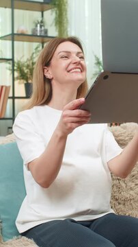 Pregnant middle-aged woman at home sees job approved on laptop lifts laptop laughs touches belly big joy. Caucasian girl on sofa celebrates new income milestone feels so proud hopeful for baby future.