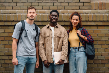 University students standing together against brick wall