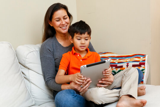 Philadelphia, Pennsylvania, USA. Native American mother and young  son reviewing homework on computer tablet