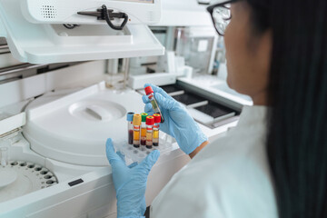 A scientist in a lab coat analyzes blood samples in a high-tech laboratory. She is focused on diagnostics and research.