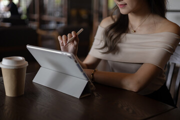 Asian woman waving hand during video call while working at cafe