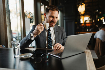 Handsome professional in a suit working remotely with a cup of coffee