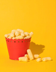 Cheesy Puffed Snacks in Red Dish on Yellow - Junk Food Concept
