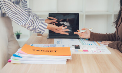 Business meeting over documents: Two business persons review documents with laptop in office room, focusing on analysis, discussion, and planning for business targets 