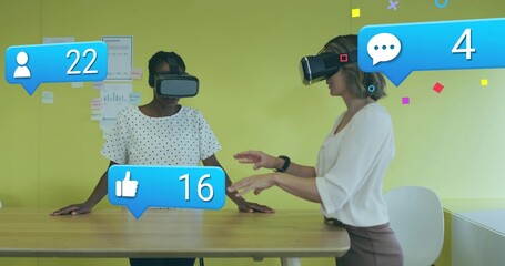 Interacting two midadult women polka and light tops using VR controls at office, with social icons