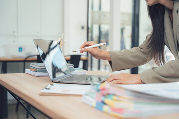 Focused Approach: In a modern office setting, a person intently uses a pen to engage with a laptop, set against the backdrop of a clean workspace.