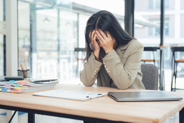 Overwhelmed at Work: A businesswoman sits dejectedly at her desk, her hands covering her face, capturing the weight of stress and the pressures of modern professional life.