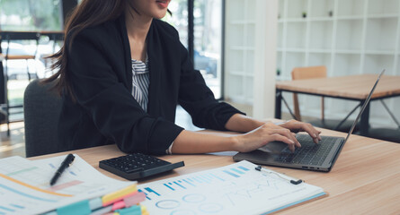 Focused work: A woman expertly navigates her laptop, her fingers dancing across the keyboard. Documents and a calculator lie close by, suggesting a day focused on efficiency.