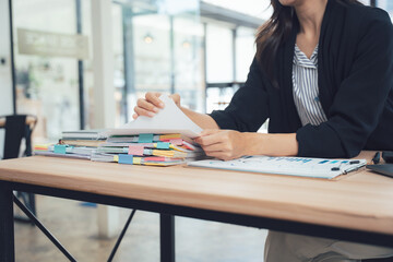 Organized Efficiency: A professional carefully reviews a stack of documents on a wooden desk, symbolizing the attention to detail and organized efficiency that drives success. 