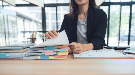 Efficiency in Office: A focused professional meticulously organizes paperwork at a modern workstation. The scene showcases organization, productivity, and modern work environment.