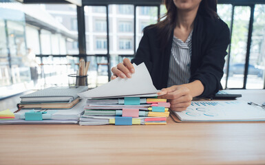 Efficiency in Detail: A focused professional meticulously manages a stack of documents on a desk, highlighting organizational skills and attention to detail.