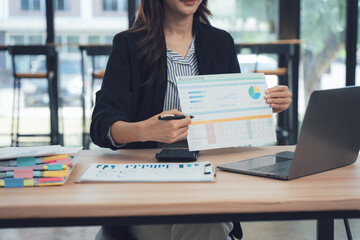 Businesswoman's Report Presentation: A focused businesswoman, presenting a comprehensive report with graphs, data sheets, and a laptop, highlighting the dynamic landscape of modern business.