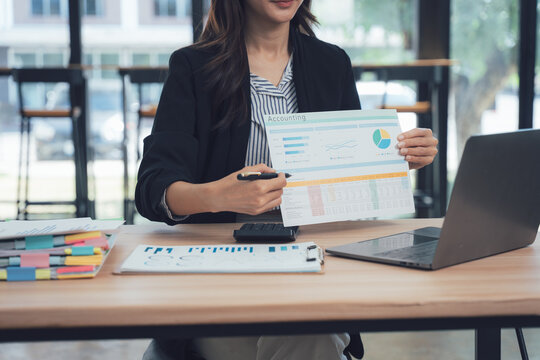 Businesswoman's Report Presentation: A focused businesswoman, presenting a comprehensive report with graphs, data sheets, and a laptop, highlighting the dynamic landscape of modern business.