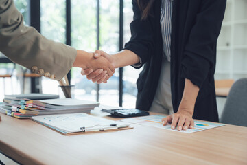 Handshake Deal: A formal handshake seals a successful business deal, symbolizing agreement, trust, and partnership, set against a modern office background.