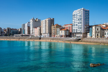 San Lorenzo Beach in Gijon, Asturias, Spain. Colorful Travel Photo with a View of Tall Modern Buildings in the Seaside Resort on the Cantabrian Sea.