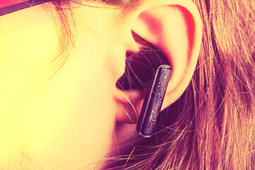 Person listens to music with wireless earbuds in a casual setting during the day