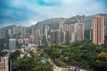 Fototapeta premium Hong Kong, China : residential high rise buildings surrounded by dense green vegetation on hillside urban landscape