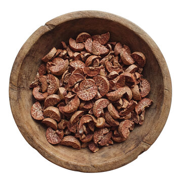 A wooden bowl filled with sliced and dried areca nuts.