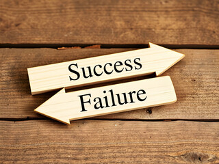 Success and Failure Wooden Arrows Pointing Opposite Directions on a Rustic Wood Background
