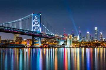 Ben Franklin bridge and Philadelphia skyline, at night with colorful reflections un Delaware river.