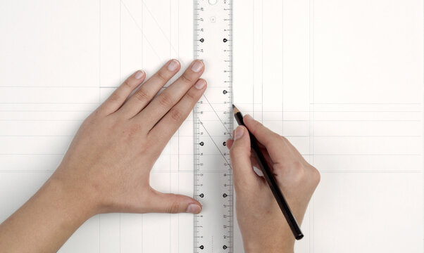 a woman's hands drawing with rulers on paper
