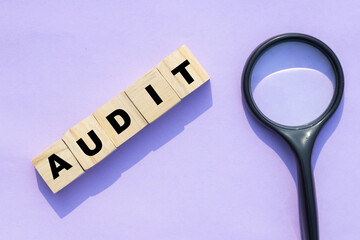 audit concept with wooden blocks and magnifying glass on light purple background for inspection and analysis