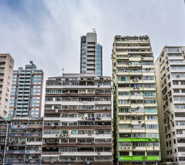 Hong Kong, China : dense residential apartment blocks showing ageing mid-century housing next to modern high-rise tower. Urban density and housing pressure in Kowloon