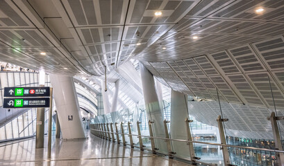 Naklejka premium Hong Kong West Kowloon Station, Hong Kong, China, 1 March 2025: interior architectural view of the high speed rail terminal showing curved ceiling structure and glass reflections