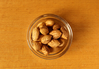 Bowl of nuts on a wooden surface shows various kinds of nuts ready for snacking or cooking