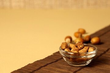 Bowl of nuts placed on a wooden surface with scattered nuts nearby during a simple snack time...