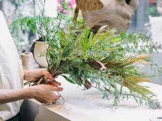 室内で葉や枝を束ねたナチュラルなグリーンアレンジメント