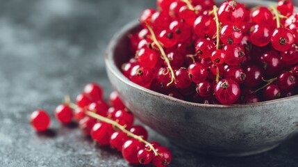 Fresh red currants in rustic bowl on dark surface.