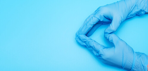 The heart, figure built from the hands in blue rubber medical gloves on a blue background.
