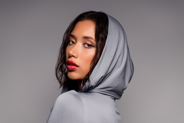 Stylish young woman in a hooded outfit posing gracefully with captivating makeup and feminine charm