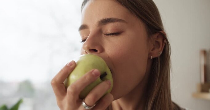 Young smiling woman eating a green apple