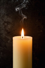 Minimalist candle flame glowing softly against dark textured background