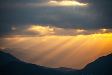Bright sunset over the silhouette mountains at evening time.