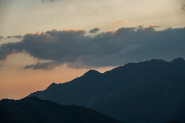 Obraz premium Bright sunset over the silhouette mountains at evening time.