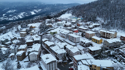 Aerial view of a small Italian village covered in winter snow during the day Le Bore, Parma, Italy