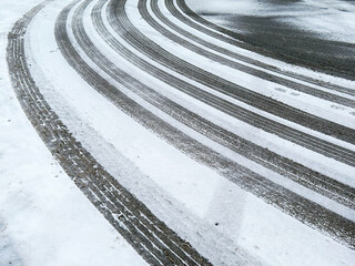 Curved tire tracks on a snow-covered road illustrate winter driving conditions and road safety challenges.