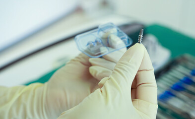 Dentist implants titanium implant as a foundation for a zirconium tooth for aesthetic purposes in the dentition. Dental assistant hands the steep implant.