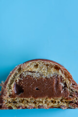 Half of a chocolate bonbon showing internal texture of waffles and praline center. Top view of a delicious unhealthy snack isolated on blue with copy space. Photo