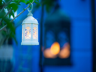 Decorative white lantern (Fanoos) glowing on nature background for Ramadan and Eid Greeting.