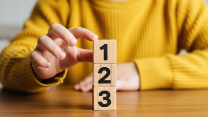 Child s hand gently holding wooden blocks stacked with numbers one two and three