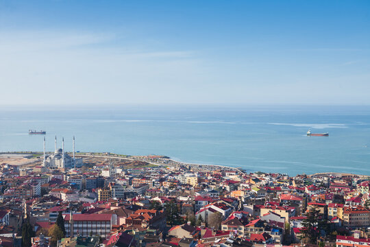 A low-angle shot of a majestic, earth-toned brick iwan with intricate geometric tilework under a clear blue sky, showcasing the grand scale of Islamic architecture.