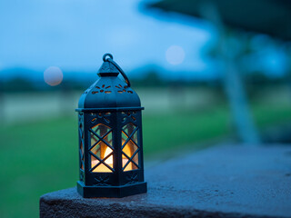 Decorative white lantern (Fanoos) glowing on nature background for Ramadan and Eid Greeting.