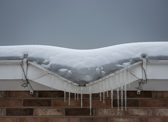 Residential White Gutter with Heavy Snow and Ice, Featuring Dripping Icicles, Symbolizing Winter Weather Challenges, Home Maintenance, and Cold Season