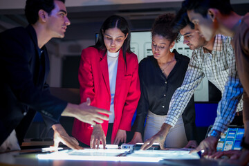 UI/UX design team conducting a workshop to review mobile app prototypes. Front-end developers and visual artists discussing web layout strategy on a large screen in a modern tech startup office.