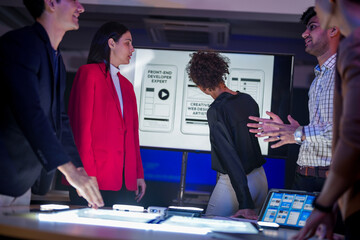 UI/UX design team conducting a workshop to review mobile app prototypes. Front-end developers and...