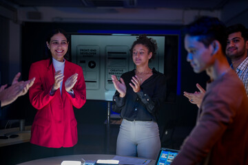 Creative UI/UX design team analyzing mobile app wireframes on illuminated digital touch table. Diverse developers brainstorming web layout strategy in modern high-tech office at night.